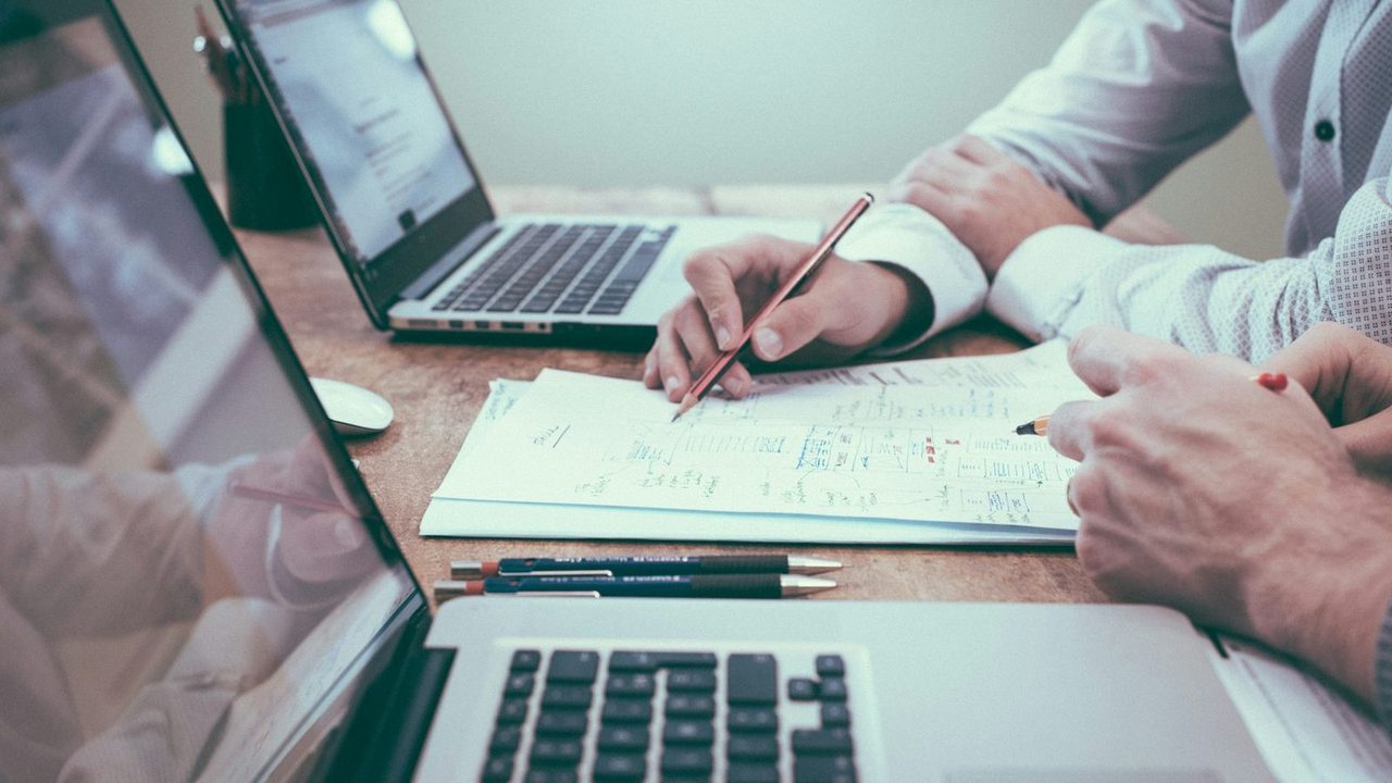 Hands reviewing documents and plans at a desk