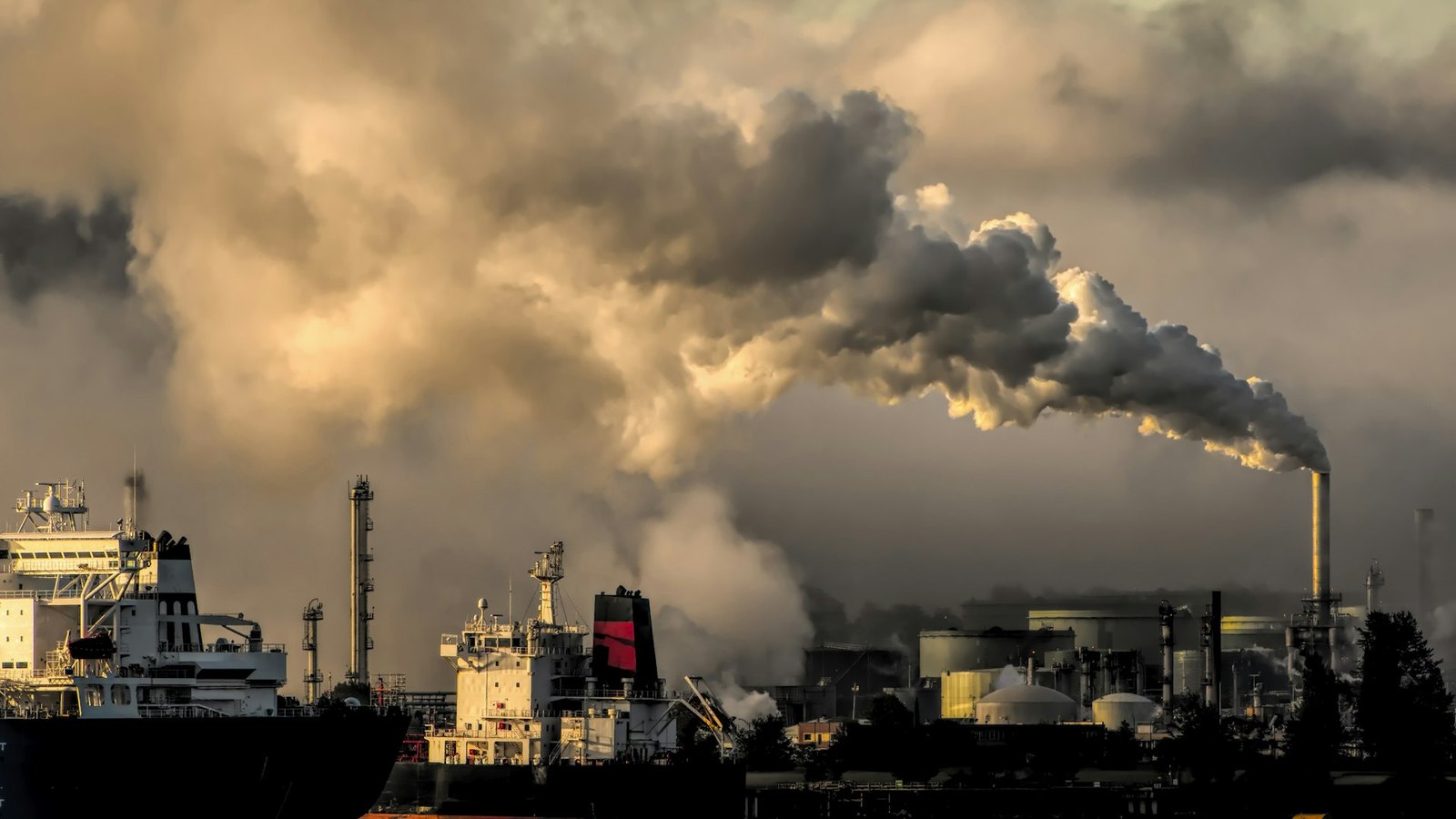 Industrial port with smokestack emissions at dusk